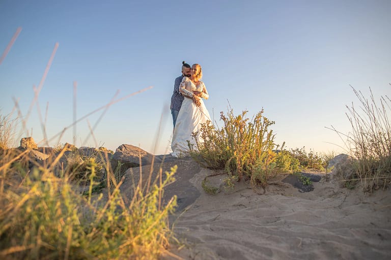 couple de marié durant la day after qui se font un câlin à la plage en couché de soleil photographier par un photographe de mariage.