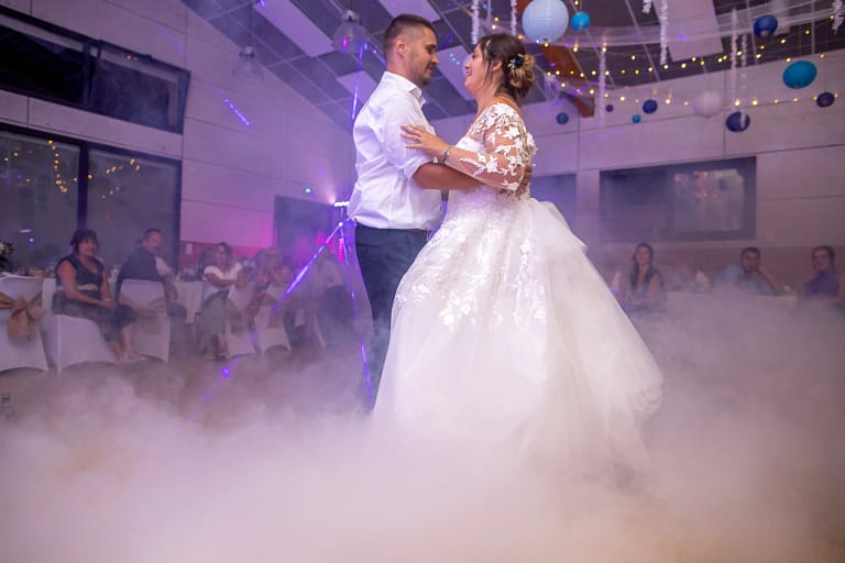 Photographie de mariage de Christelle et Fabien lors de leurs première danse. Il se regarde amoureusement, tandis qu'ils se font envelopper de fumer progressivement. Photographie prise par un photographe de mariage professionnel